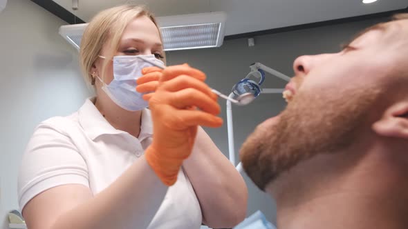 Female Dentist Treats Young Man's Teeth Dentist's Office