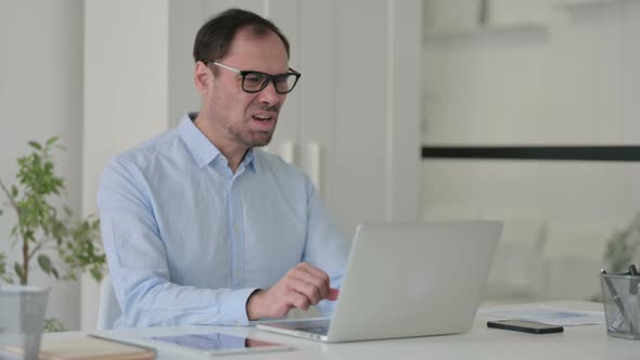 Middle Aged Man Reacting to Loss While Using Laptop in Office