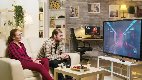 Cheerful Girlfriend Talking with Her Boyfriend While He's Playing Video Games