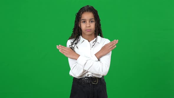 Front View of Serious Teenage African American Girl with Crossed Hands No Gesture Posing on Green