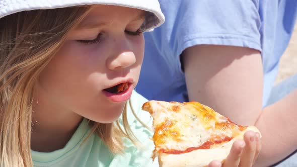 Little Girl Eating Pizza on the Beach