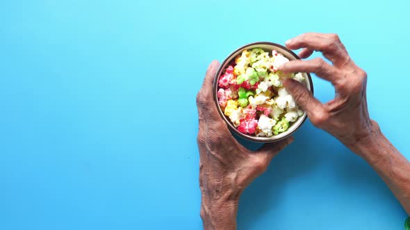 Top View of Elderly Women Hand Holding a Bowl of Colorful Popcorn