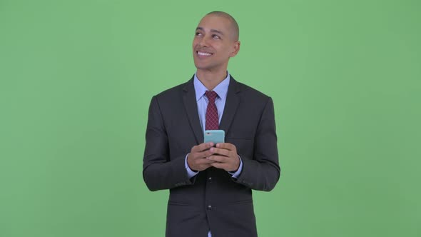 Happy Bald Multi Ethnic Businessman Thinking While Using Phone and Calling