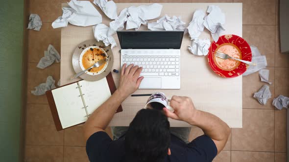 Male Freelancer Working on Laptop at Home in Clutter and Chaos