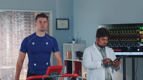 Mixed Race Doctor Performing Stress Test While the Athlete Walking on Treadmill