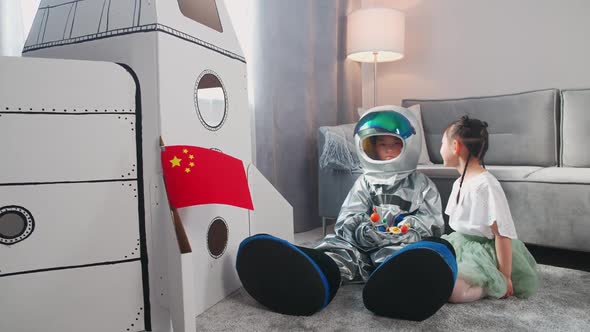 Asian Kids Play in the Living Room at Home a Boy in an Astronaut Costume Sitting on the Floor with