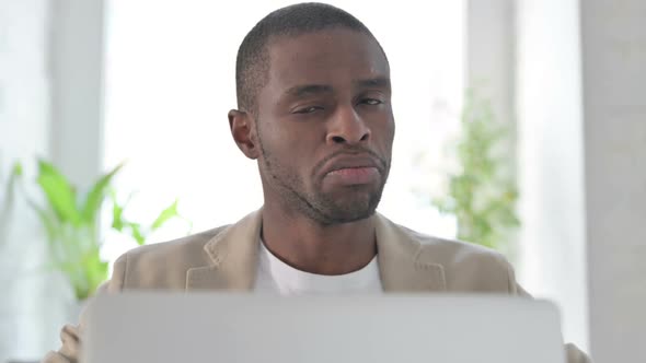 Close Up of African Man with Laptop Shaking Head As No Sign