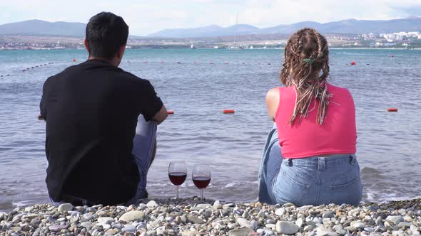 Couple sitting at seaside with red wine glasses