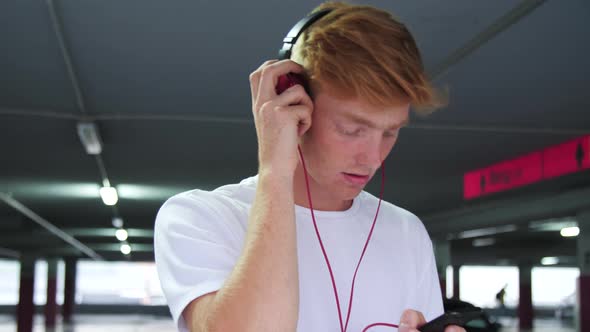 Young Man In Earphones Listening Music And Using Phone