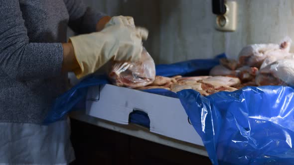 Closeup View of Hands in Gloves Packing Chicken Legs From a Box Into Individual Plastic Bags