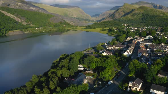 Tilt Up Reveal of Touristic Lakeside Village in European Mountains in Wales - Aerial Drone