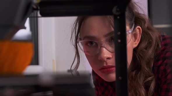 Young Woman with Protective Eyeglasses Using 3D Printer