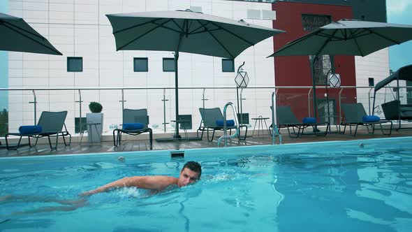 Tourist of european appearance in a hotel is swimming in a pool with blue water in summer on resort