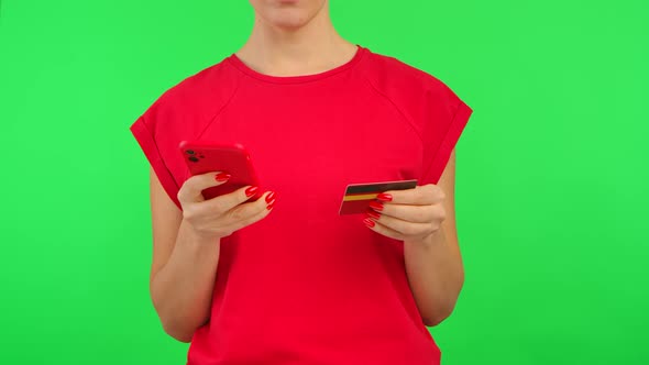 Woman in Red Tshirt Makes an Online Purchase with a Credit Card and Smartphone with Workspace Mock