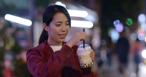 Woman enjoy iced bubble tea in city at night