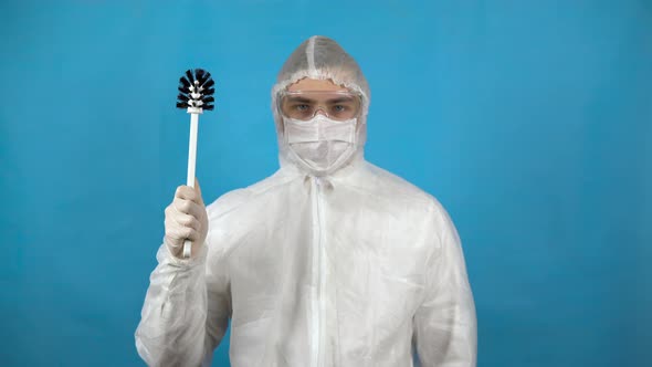 A Young Man in a Protective Suit with a Toilet Brush in His Hand. A Man Is Ready for Cleaning on a