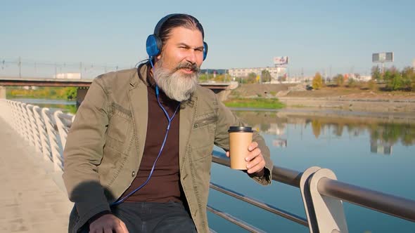 Bearded Middleaged Man with Headphones Listens to Music Sings Along and Nods to the Beat of the