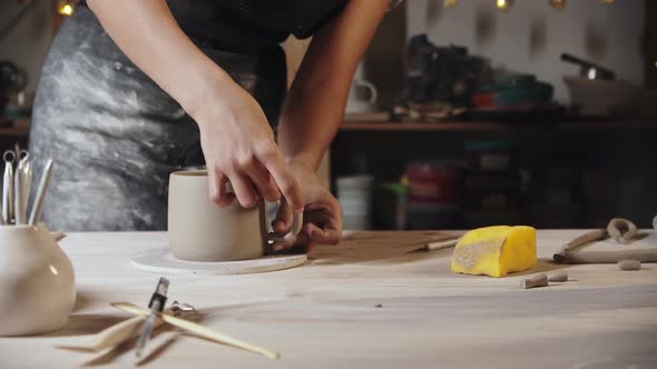 Young Woman Potter Trying on a Clay Handle to a Cup