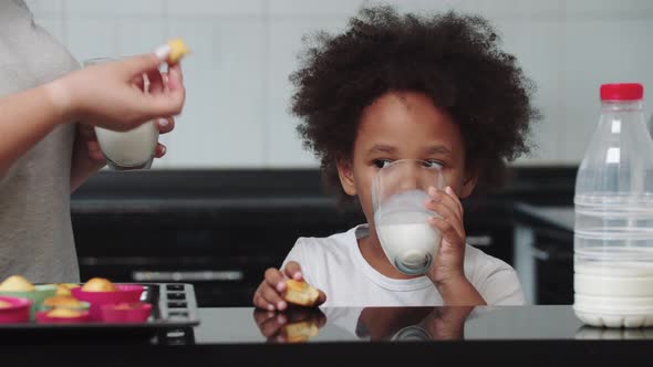 Black Mixed Little Girl Eating Cupcakes with Milk