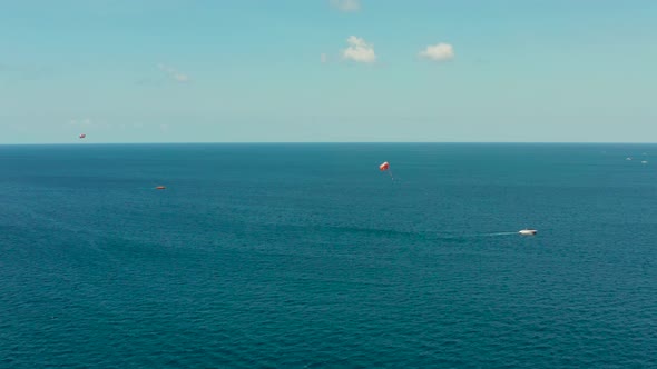 Tourists on a Parachute Over the Sea