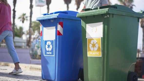 Female Volunteers Rolling Containers for Separate Waste Collection Away in Mediterranean Country