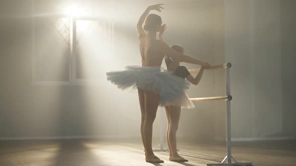 Side View of Young Ballet Teacher and Little Student Moving Hands in Slow Motion Standing at Ballet