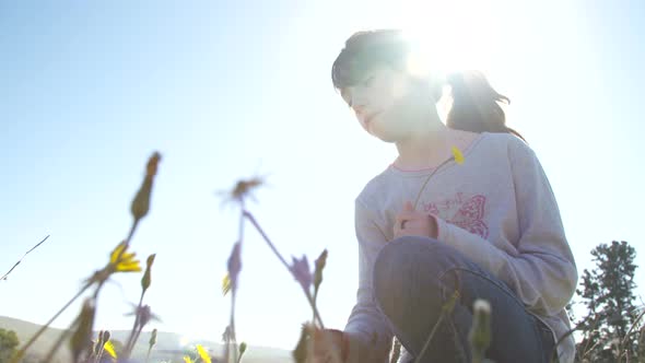 Young girl smelling a flower outdoors in nature