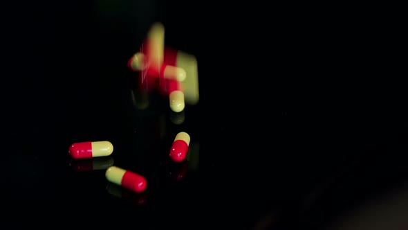 Closeup of Pills Falling on Black Table Slow Mo