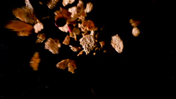 Berries and Cornflakes falling from the dark in the light and hitting on the ground in slow motion.