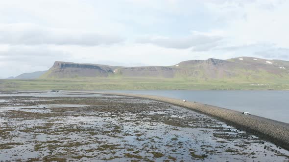 Panorama Of A Vehicle Crossing The Bridge At The Seawall In Westfjords, Iceland. aerial