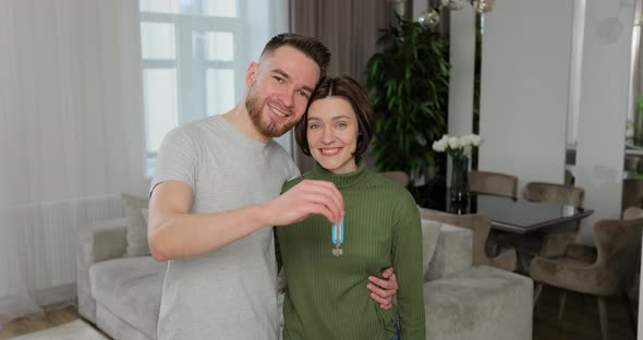 Happy Young Family Couple Looking at Camera Showing Keys Form New Apartment