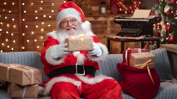 Portrait of Male Santa Claus with Natural Beard Giving Gift Box