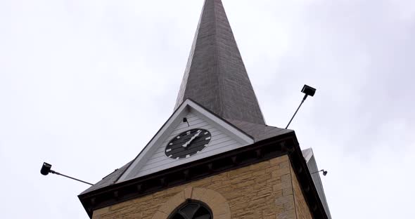 Beautiful church with overcast clouds with clock on the front.
