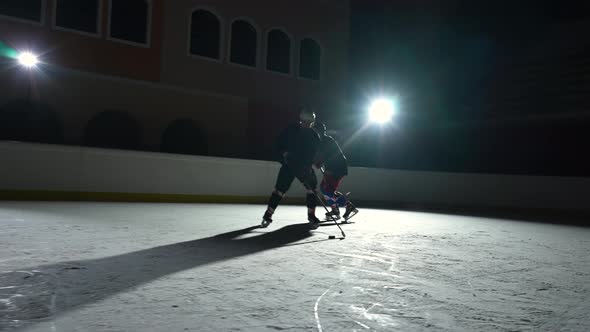 Two Men Hockey Player in Uniforms Masterfully Dribbles Hitting Puck with Stick and Forward Scores