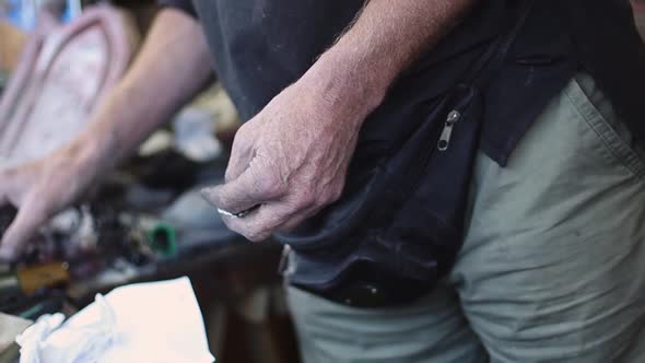 The hands of a caucasian male engraver are looking for a tool on the desktop.