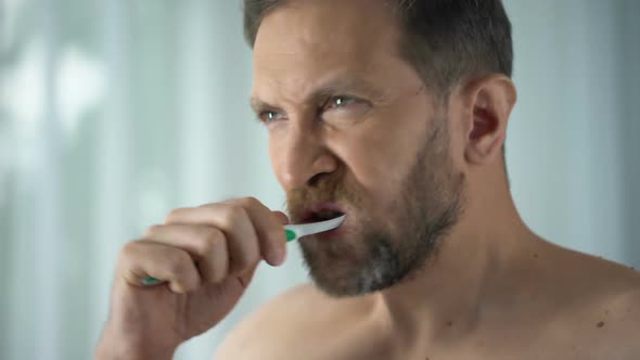 Male in Bathroom Looking at Blood Toothbrush, Oral Hygiene, Parodontosis Illness
