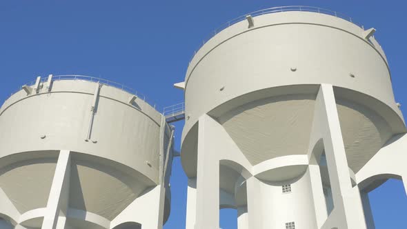 Concrete water towers in front of blue sky slow motion 4K 2160p UHD footage - Water tower made of co