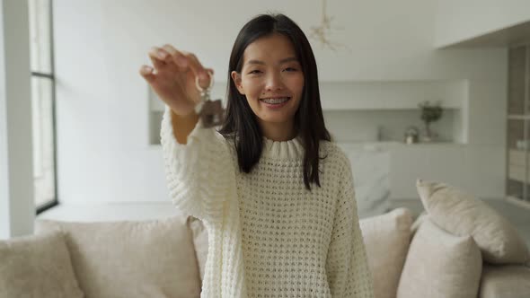 Young Asian Female Buyertenant Looks Into the Camera with Keys in Her Hand