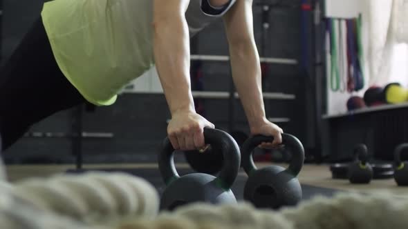 Sportswoman Doing Push-Ups with Kettlebells