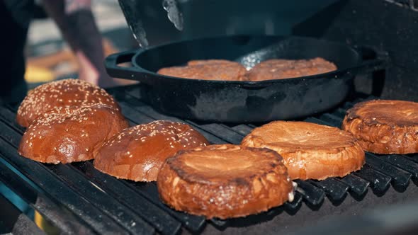 Frying patties and burger buns in a frying pan and grill. BBQ, slow motion