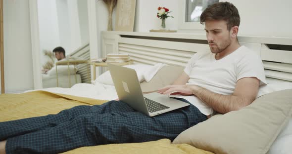 Seriously Man Working on His Laptop Sitting on His