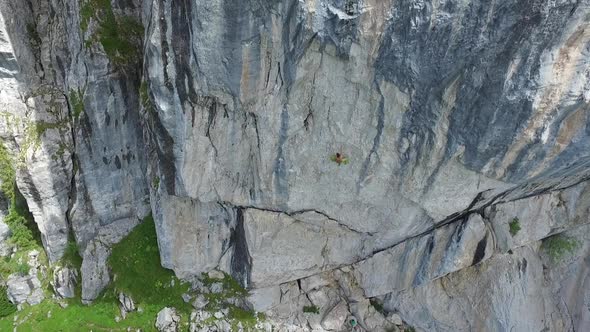 Aerial drone view of a man rock climbing up a mountain
