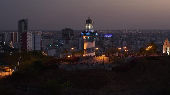 Aereal view of Cerro Santa Ana in the night. In the middle the lighthouse turning off and on. Guayaq