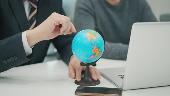 Senior Man CEO at a Business Meeting with a Colleague. Hand Rotates the Globe