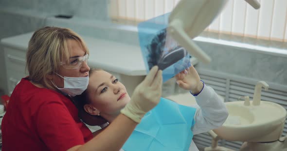 Pretty Woman Dentist Looks at the Patient's X-ray and Tells How the Teeth Will Be Treated