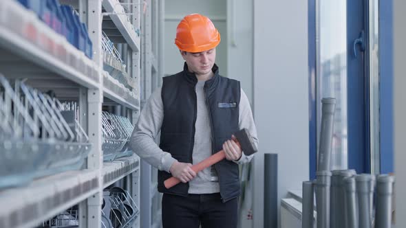 Cheerful Male Worker in Hard Hat Posing with Big Hammer in Hardware Store