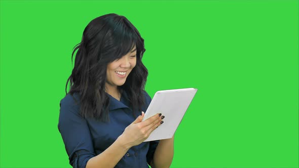 Smiling Young Woman Working on Tablet Computer on a Green Screen, Chroma Key