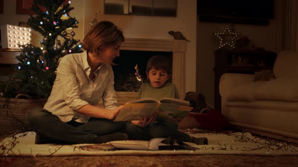 Mother reading book with son on Christmas eve