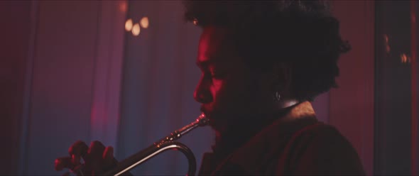 Professional musician playing the trumpet in a room with red and blue neon lights