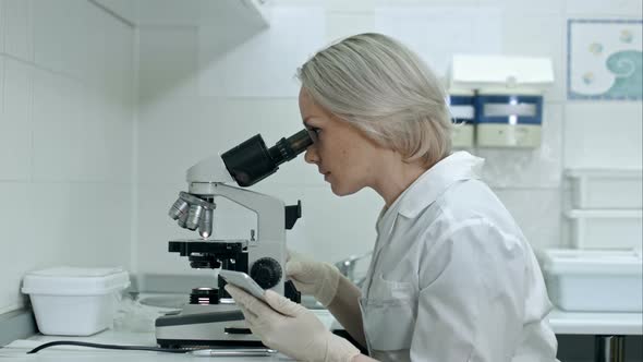 Scientist Working with Microscopes and Smartphone in Chemical Lab